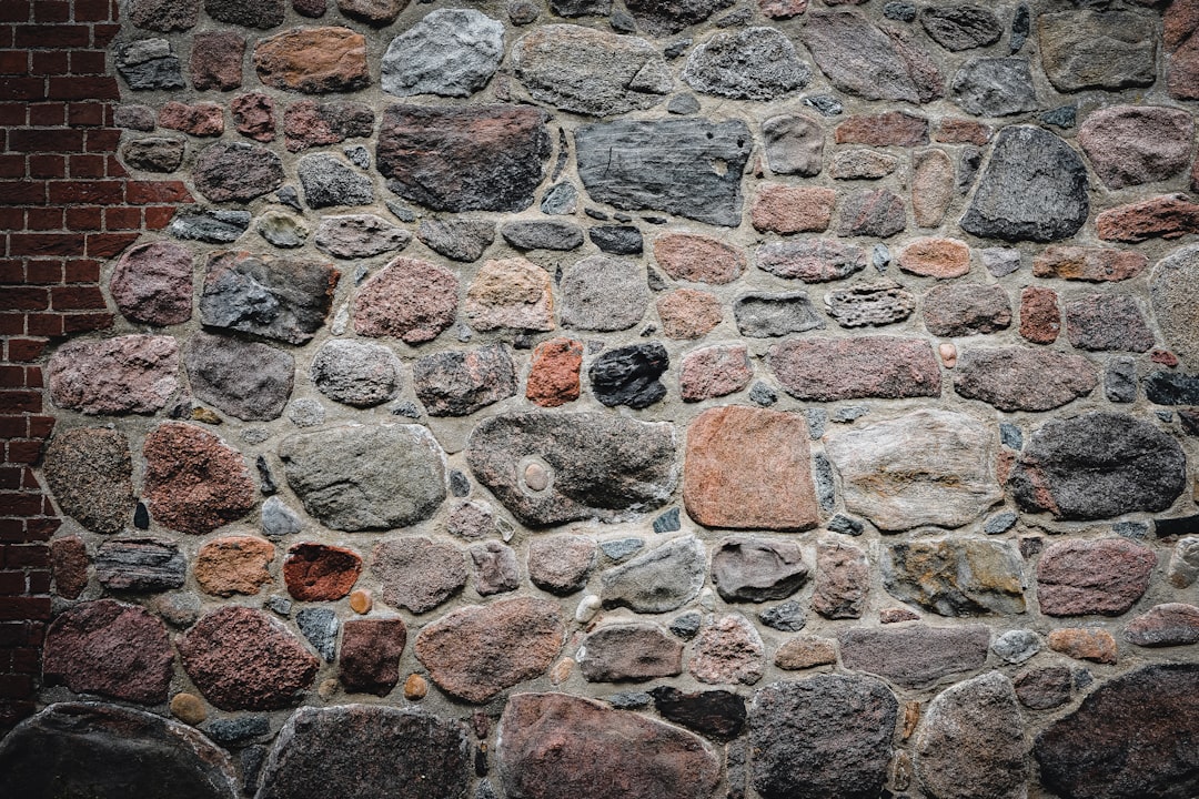 rustic-stone-wall-with-a-small-section-of-red-brick-nwm4v55rb-e